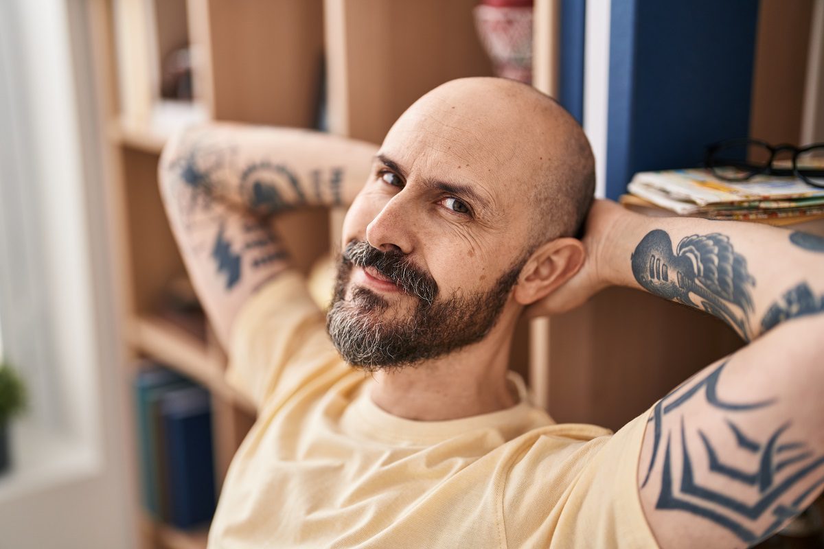 Young bald man relaxed with hands on head